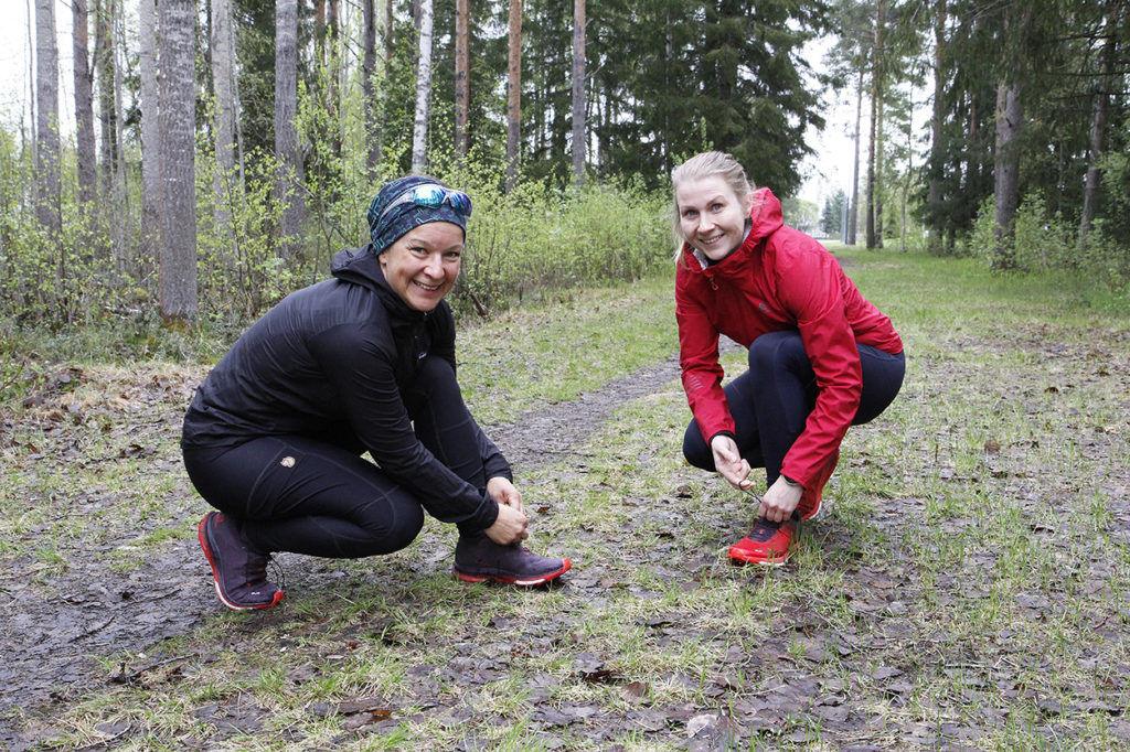 Naiset sitovat kengännauhojaan.